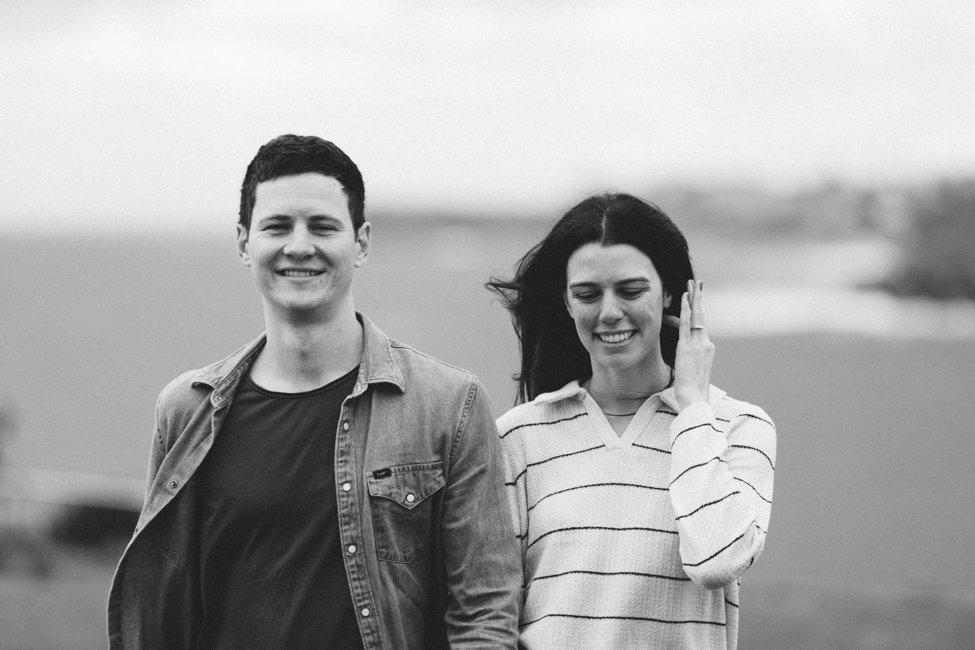 A couple laughing into the wind, in black and white.
