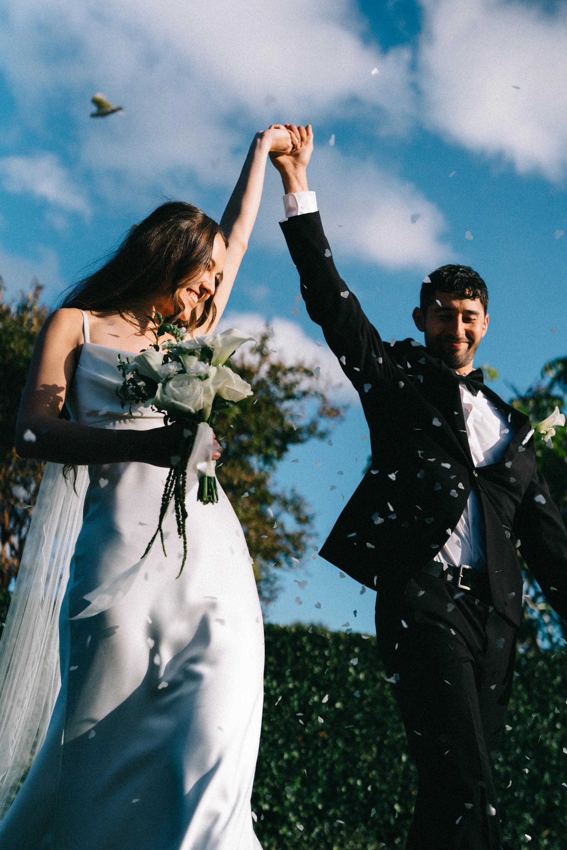 A couple celebrating under falling confetti against the sky, Sydney
