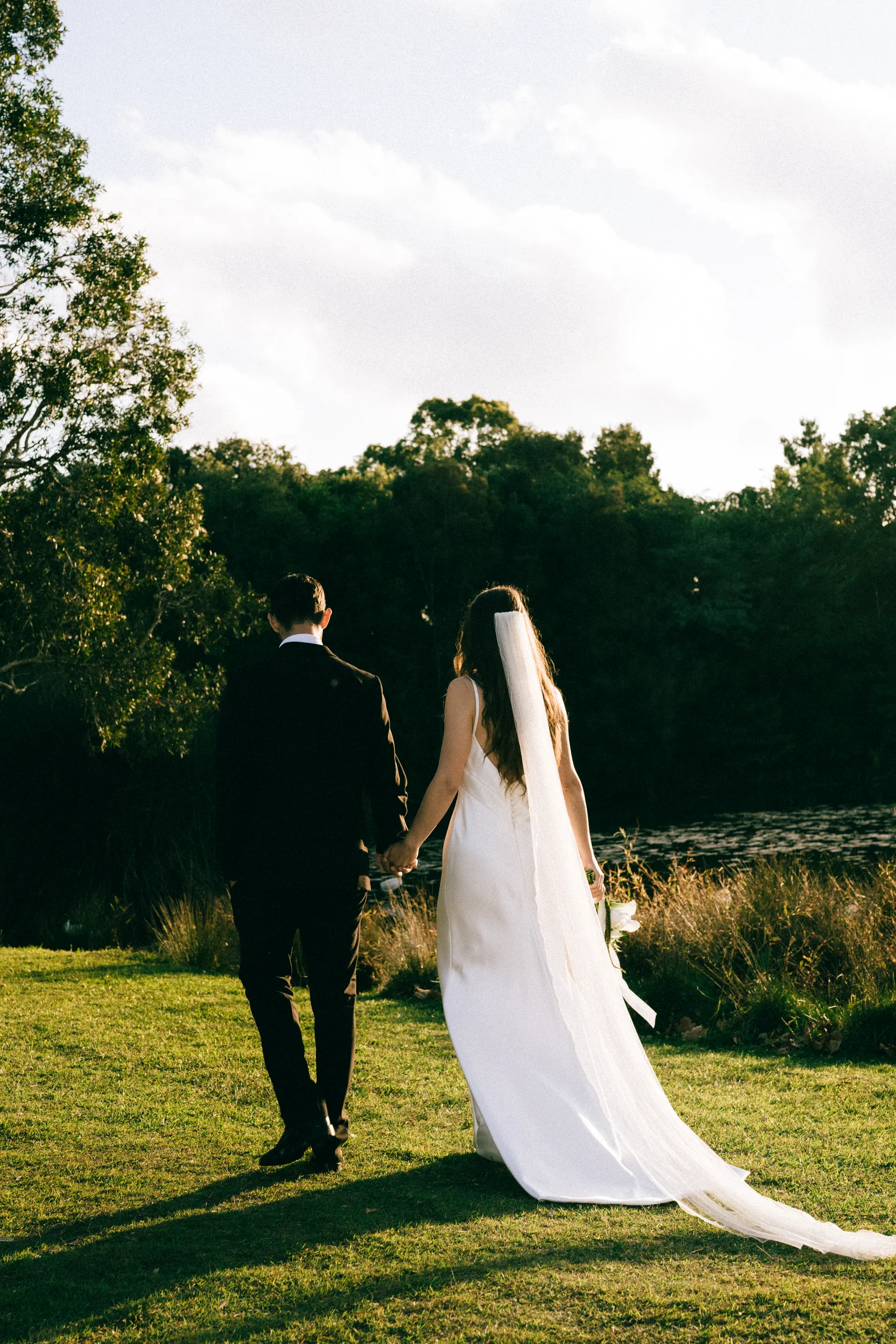 A bride running across a clifftop lawn by the sea.